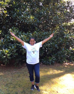 Founder Shundrika Williams celebrating with arms raised outdoors in a Vitality Village shirt