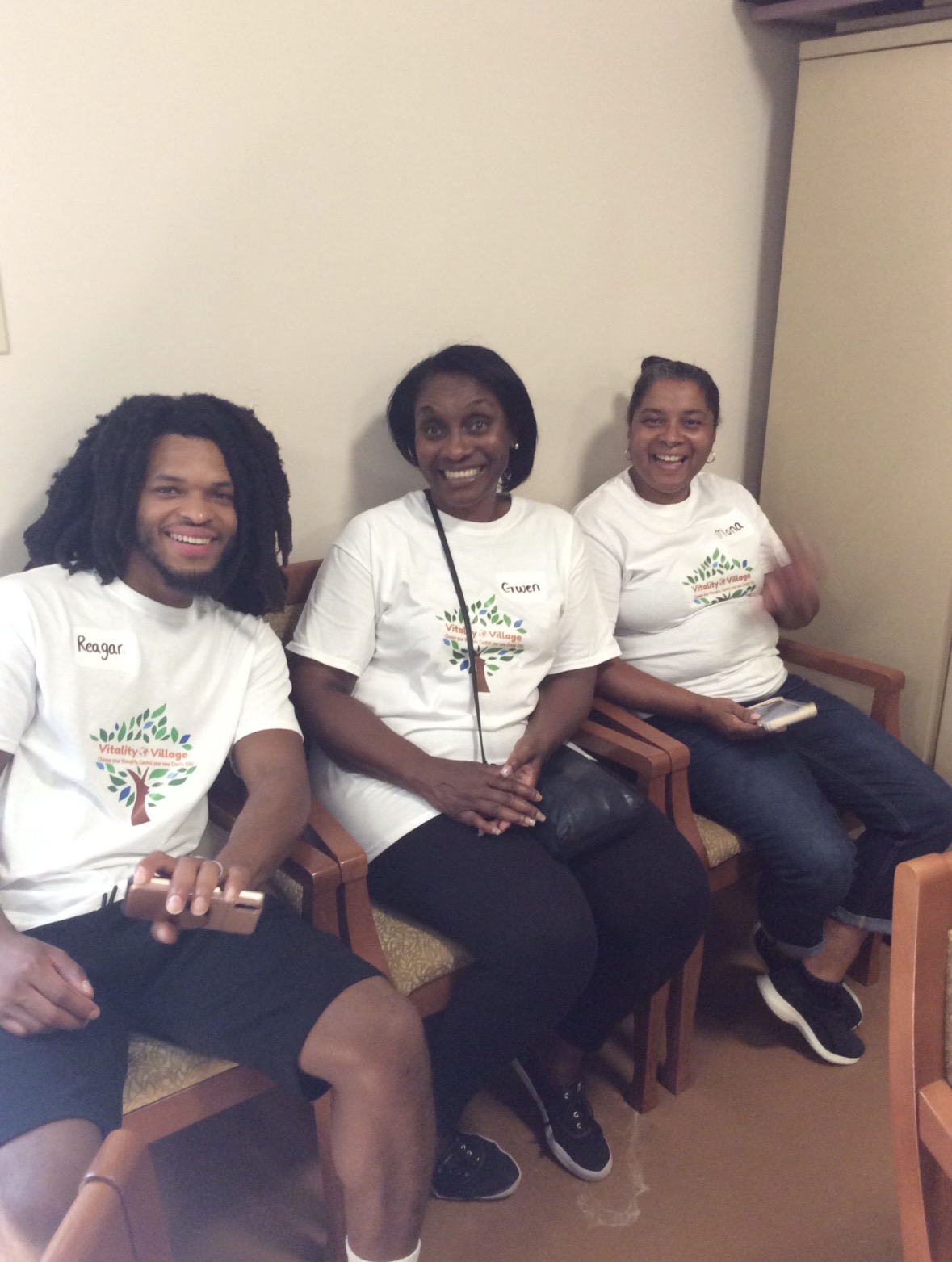 Three Vitality Village members in branded t-shirts smiling together