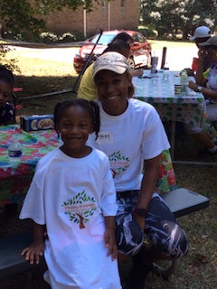 Vitality Village volunteer and child at a community picnic in matching shirts